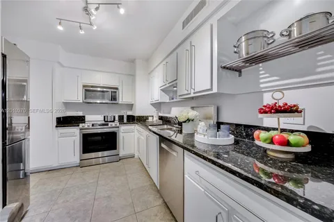 a kitchen with kitchen island granite countertop a sink stainless steel appliances and cabinets