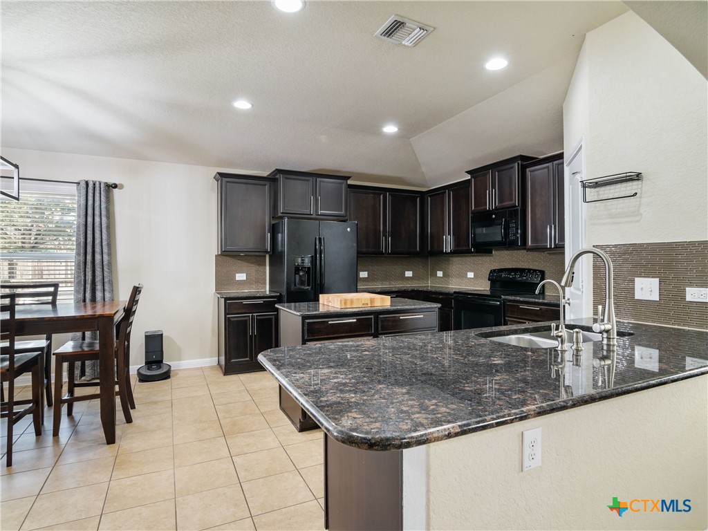 2231 Westover Loop New Braunfels, TX 78130 - Photo 13 of 35 a kitchen with granite countertop a sink a stove counter space and cabinets