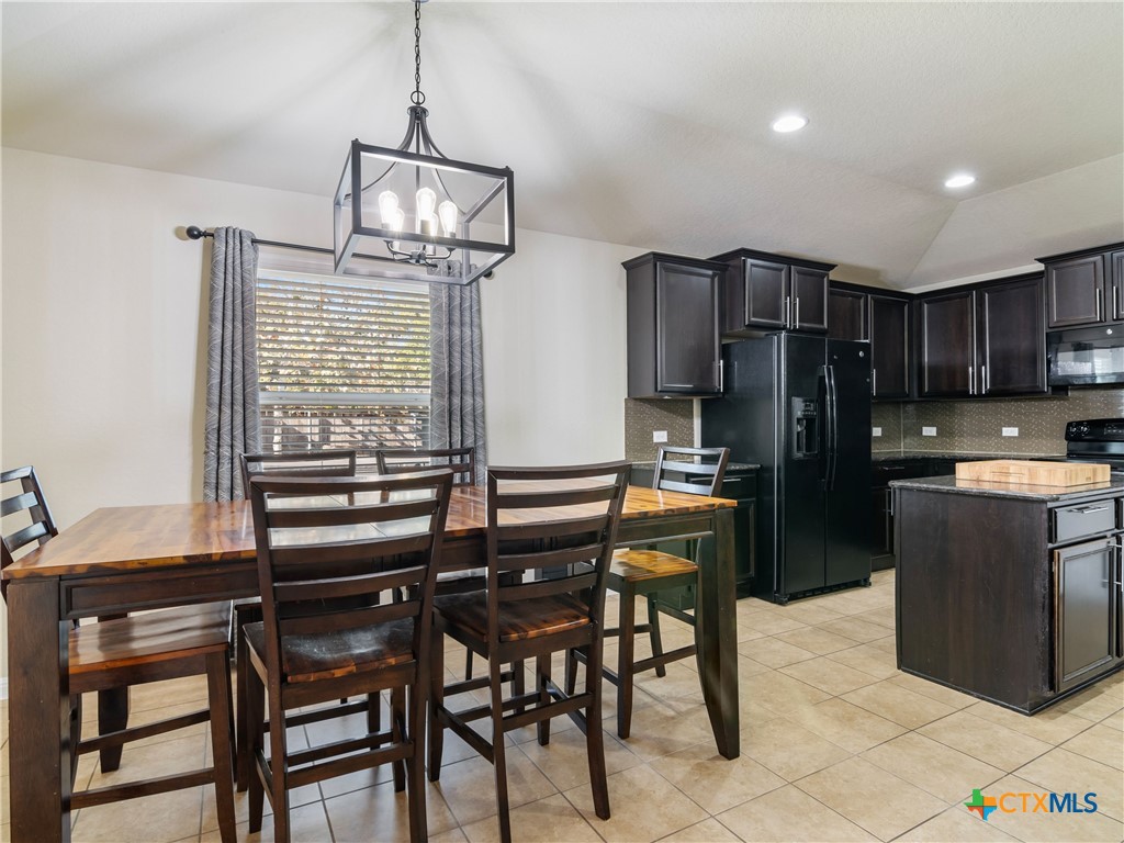 2231 Westover Loop New Braunfels, TX 78130 - Photo 20 of 36 a kitchen with stainless steel appliances kitchen island granite countertop a table chairs and a refrigerator