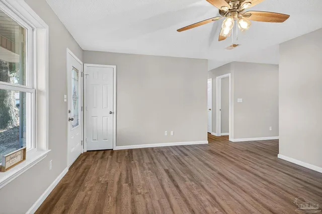 a view of an empty room with wooden floor and a window