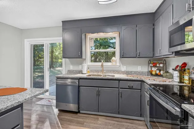 a kitchen with stainless steel appliances granite countertop a sink stove and cabinets