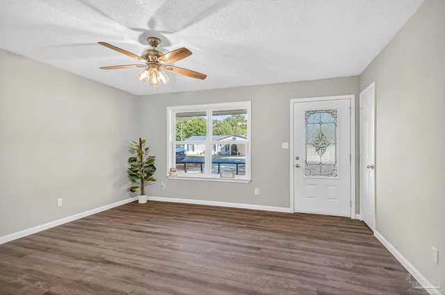 an empty room with wooden floor chandelier fan and windows