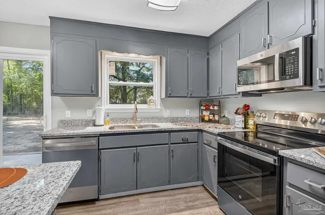 a kitchen with stainless steel appliances granite countertop a sink stove and microwave