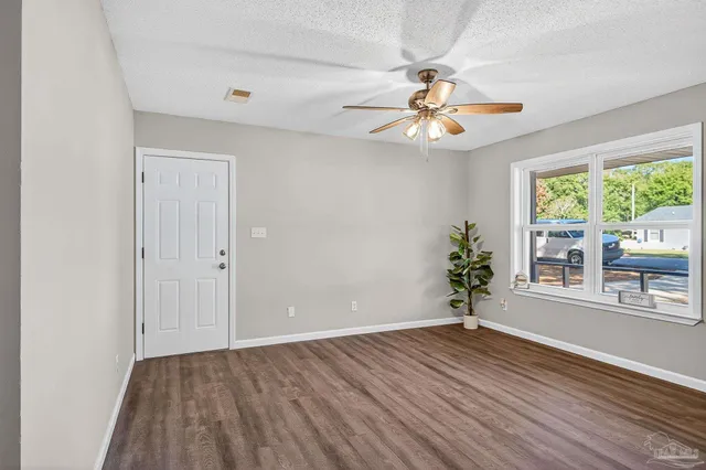 an empty room with wooden floor chandelier fan and windows