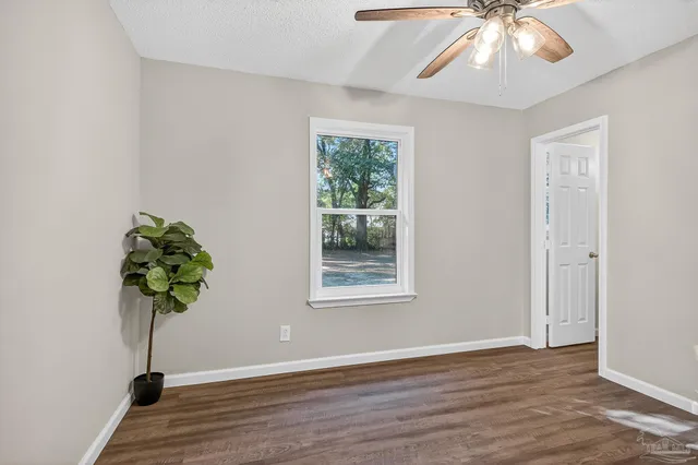 a view of an empty room with wooden floor and a potted plant