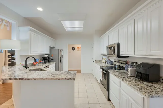 a kitchen with stainless steel appliances granite countertop a sink stove refrigerator and cabinets