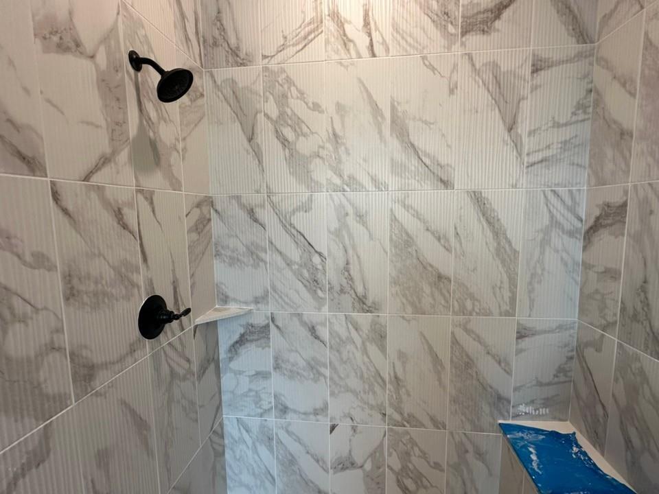 585 Brown Road Leonard, TX 75452 - Photo 17 of 29 Dual shower system featuring matte black fixtures, marble-patterned wall tiles, and textured accent tiles