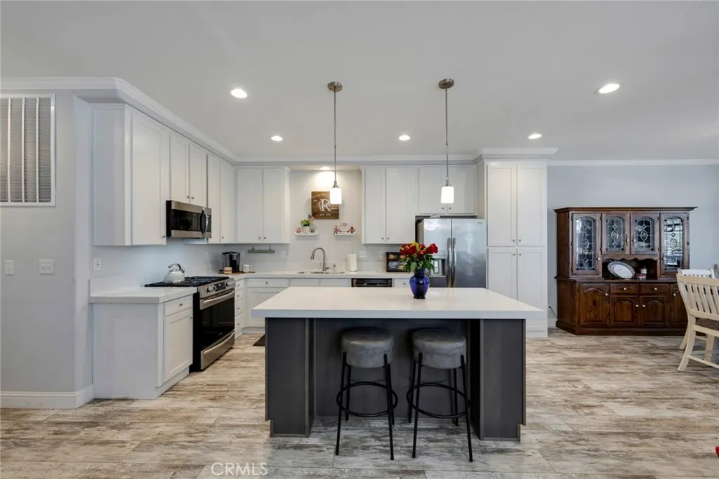 a kitchen with stainless steel appliances granite countertop a stove a sink a refrigerator a microwave oven with a dining table and chairs