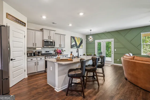 a kitchen with kitchen island granite countertop wooden floors and white appliances