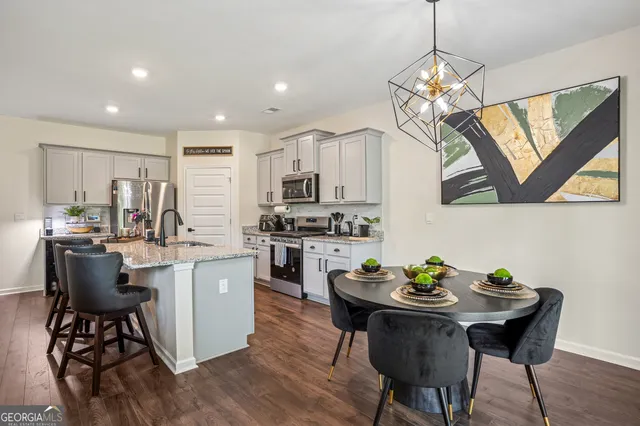 a kitchen with a dining table chairs stainless steel appliances and cabinets