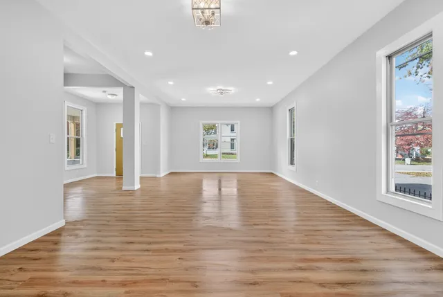 a large kitchen with stainless steel appliances granite countertop a sink dishwasher and white cabinets with wooden floor