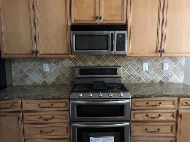 a kitchen with granite countertop white cabinets and stainless steel appliances
