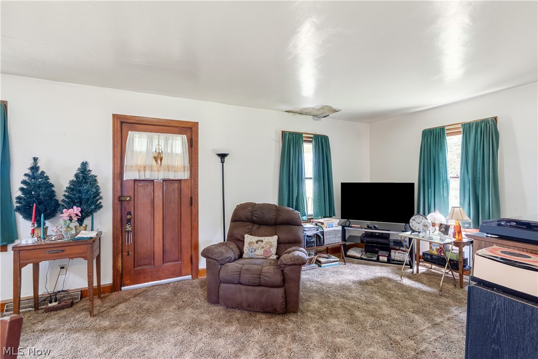 6324 Struthers Road Youngstown, OH 44514 - Photo 23 of 42 Living area featuring a paneled wood-finish door with decorative trim, multiple windows with teal drapes, and textured carpeting