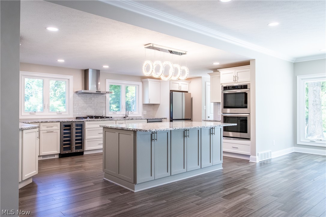 2728 Lander Road Cleveland, OH 44124 - Photo 8 of 50 Kitchen featuring a wealth of natural light, wall chimney exhaust hood, stainless steel appliances, and a kitchen island