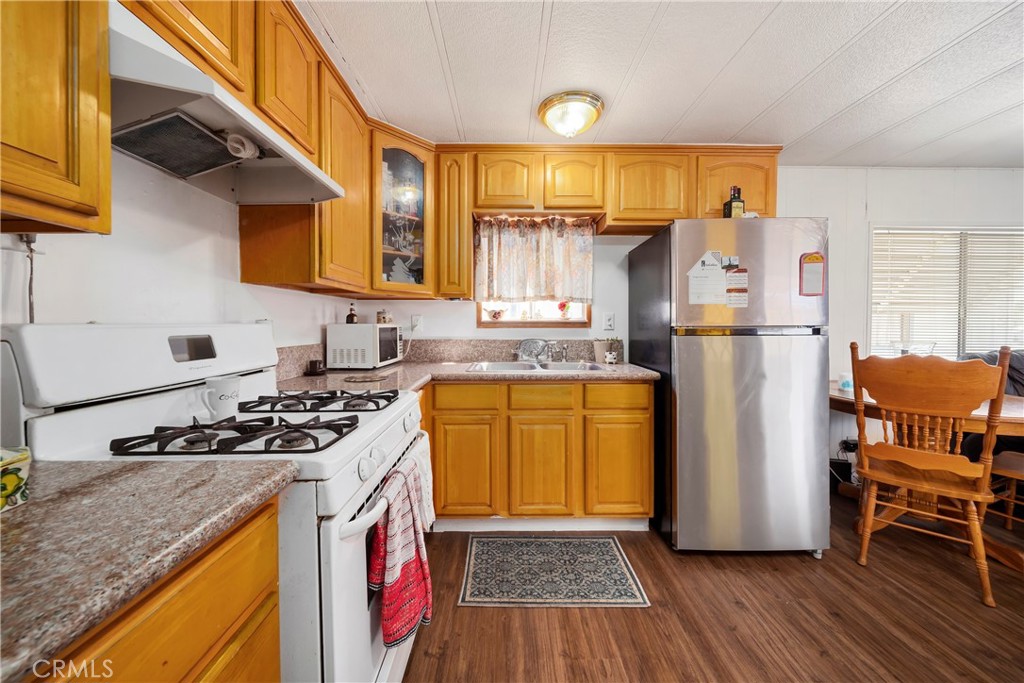 4101 Paramount Boulevard, Unit 27 Pico Rivera, CA 90660 - Photo 11 of 22 a kitchen with stainless steel appliances granite countertop a refrigerator a sink and wooden floors