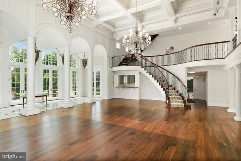 a view of a room with wooden floor chandelier and windows