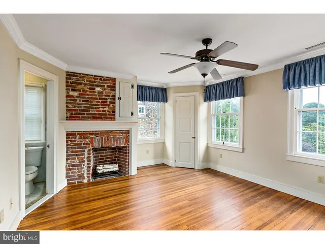 an empty room with wooden floor a fireplace and windows