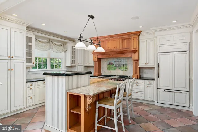a kitchen with kitchen island granite countertop a table chairs sink and cabinets