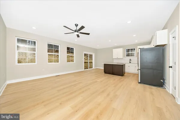 a view of empty room with wooden floor and ceiling fan