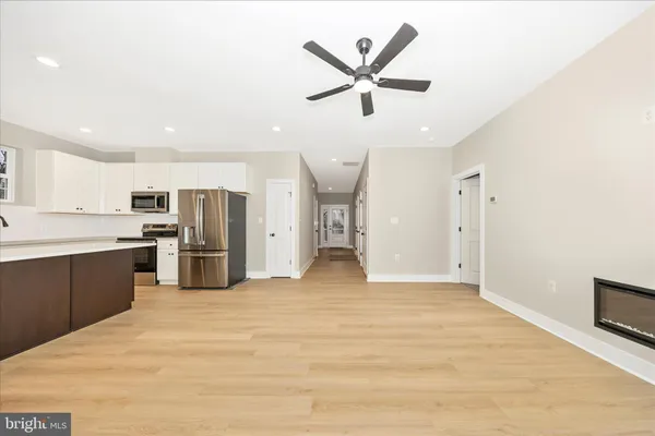 a large white kitchen with wooden floors stainless steel appliances