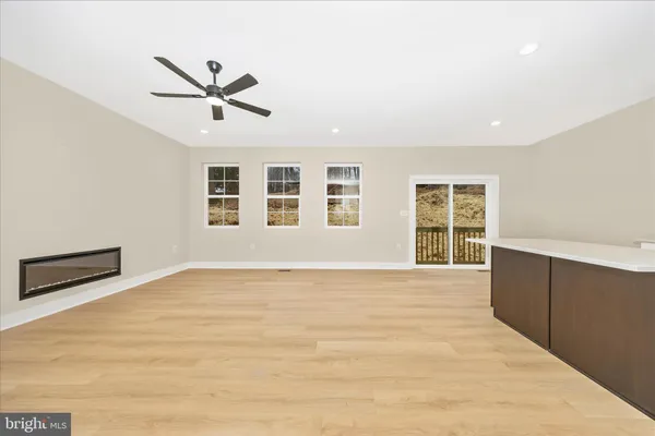 a view of an empty room with a window and a kitchen