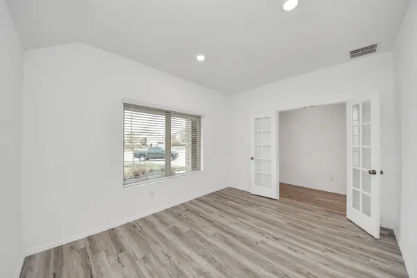 an empty room with wooden floor and windows
