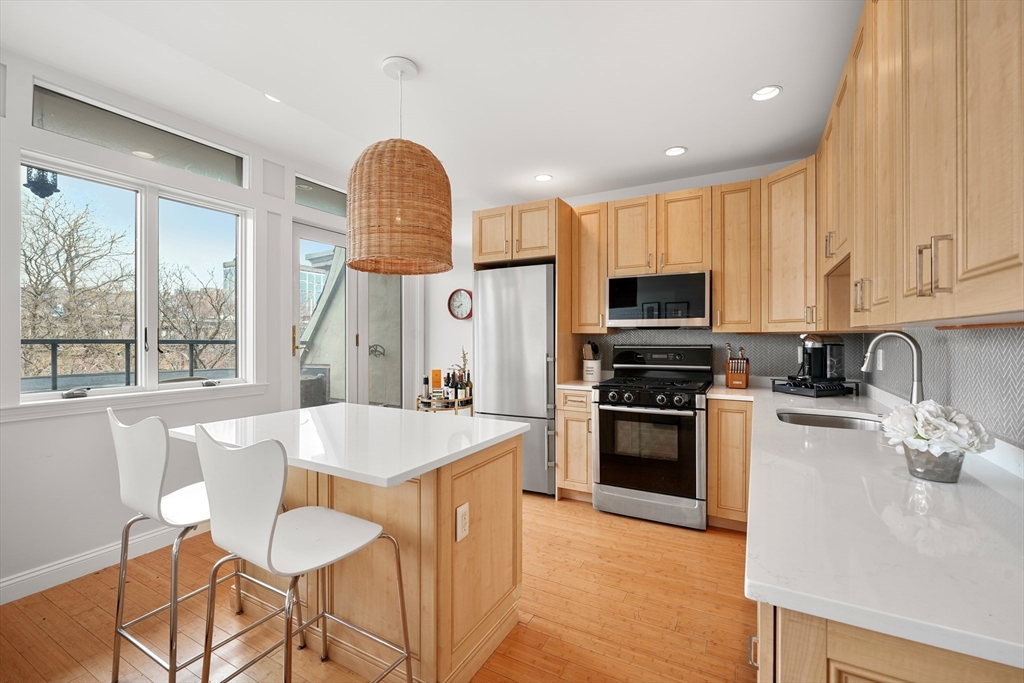 21 Worcester Square, Unit 5 Boston, MA 02118 - Photo 2 of 33 a kitchen with stainless steel appliances granite countertop a stove top oven a sink dishwasher a dining table and chairs with wooden floor