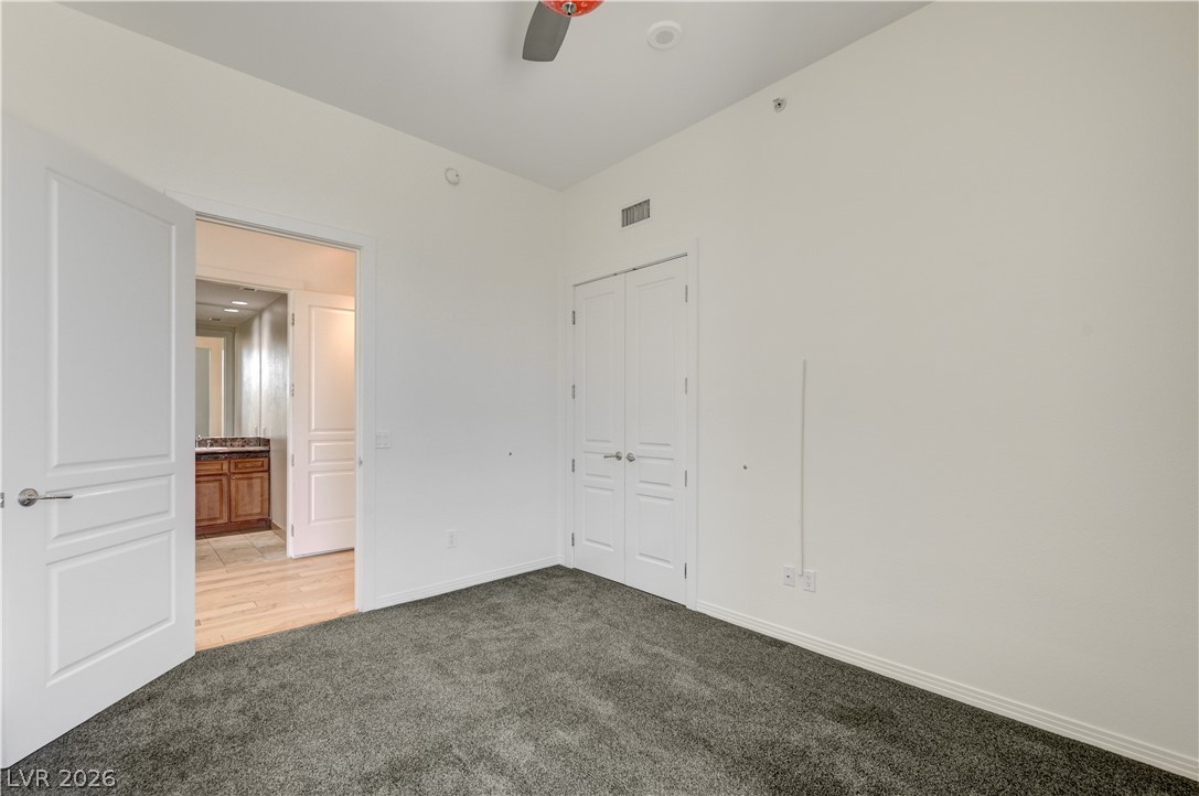 360 East Desert Inn Road, Unit 402 Las Vegas, NV 89109 - Photo 34 of 40 A well-lit bedroom with plush carpeting, offering a private retreat within.