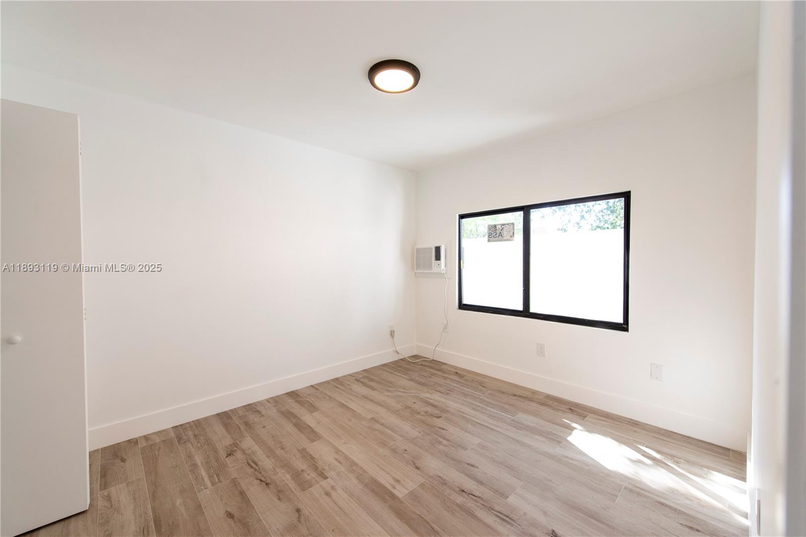 764 Northwest 36th Avenue, Unit 2 Miami, FL 33125 - Photo 5 of 11 an empty room with wooden floor and windows