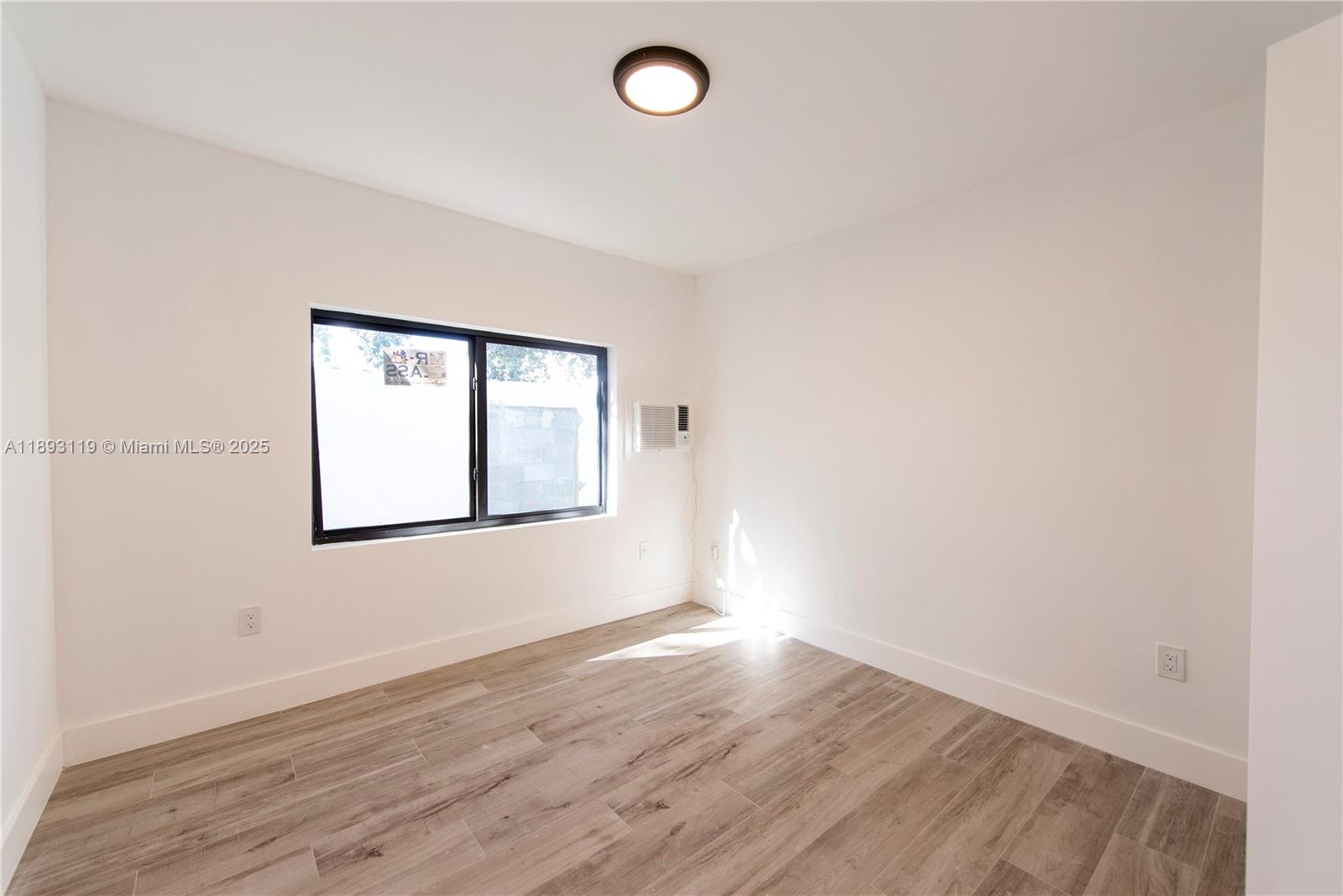 764 Northwest 36th Avenue, Unit 2 Miami, FL 33125 - Photo 7 of 11 an empty room with wooden floor and windows