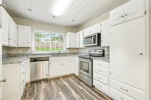 a kitchen with granite countertop white cabinets and white appliances