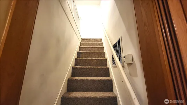 a view of staircase with white walls and white door
