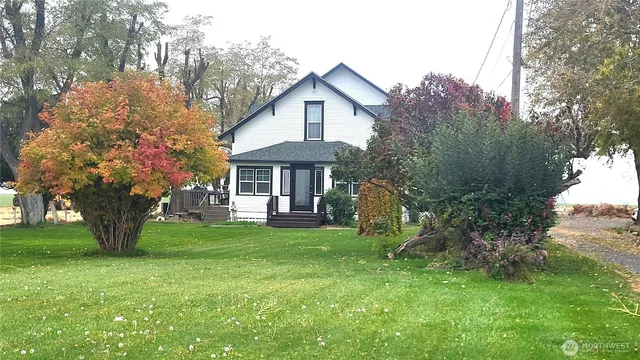 a front view of a house with a garden and trees