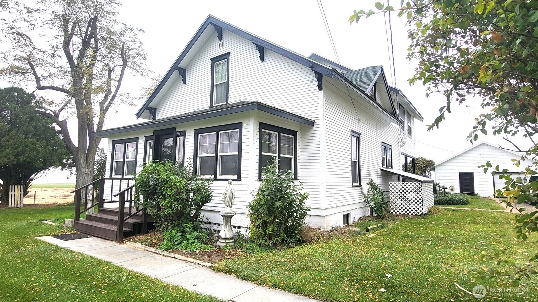 1113 South County Road Warden, WA 98857 - Photo 8 of 40 a view of a white house next to a yard with big trees