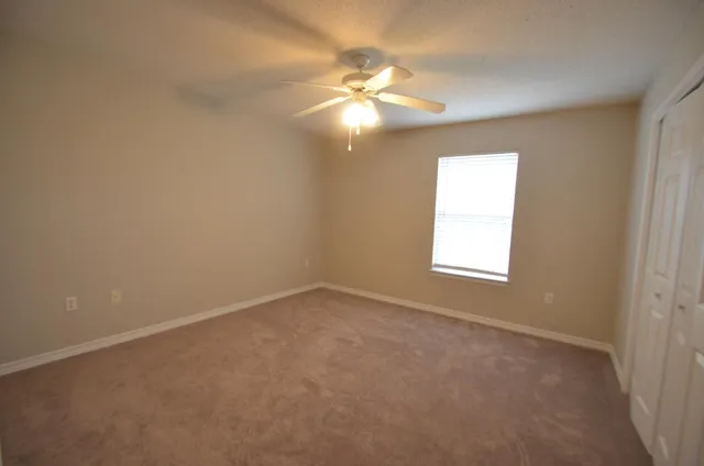 an empty room with a window and a fan