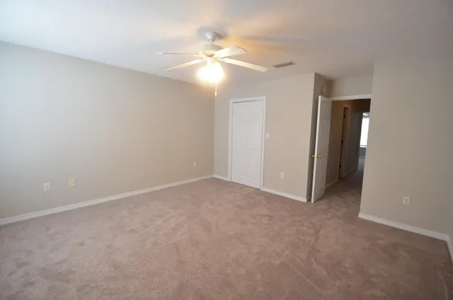 a view of an empty room with a chandelier fan