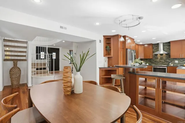 a dining room with furniture wooden floor and a kitchen view