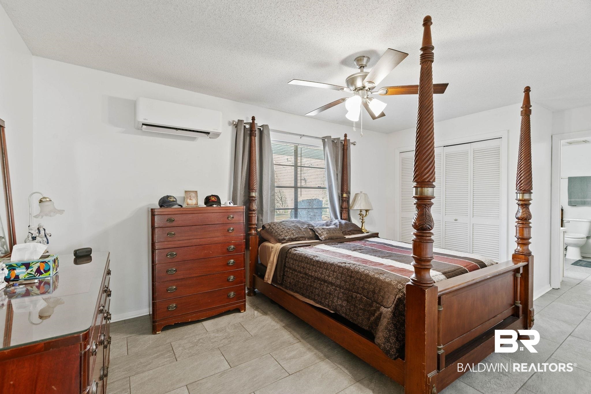 21267 Loop Road Andalusia, AL 36421 - Photo 30 of 72 Bedroom with a ceiling fan, ensuite bathroom, a textured ceiling, a wall unit AC, and light tile patterned floors