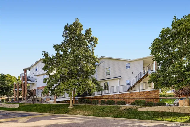 a view of a white building among the street and trees