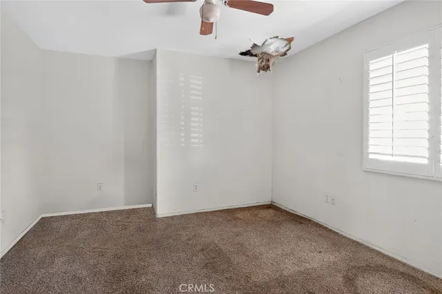 an empty room with a window and a fan