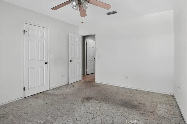 a view of an empty room with window and chandelier fan