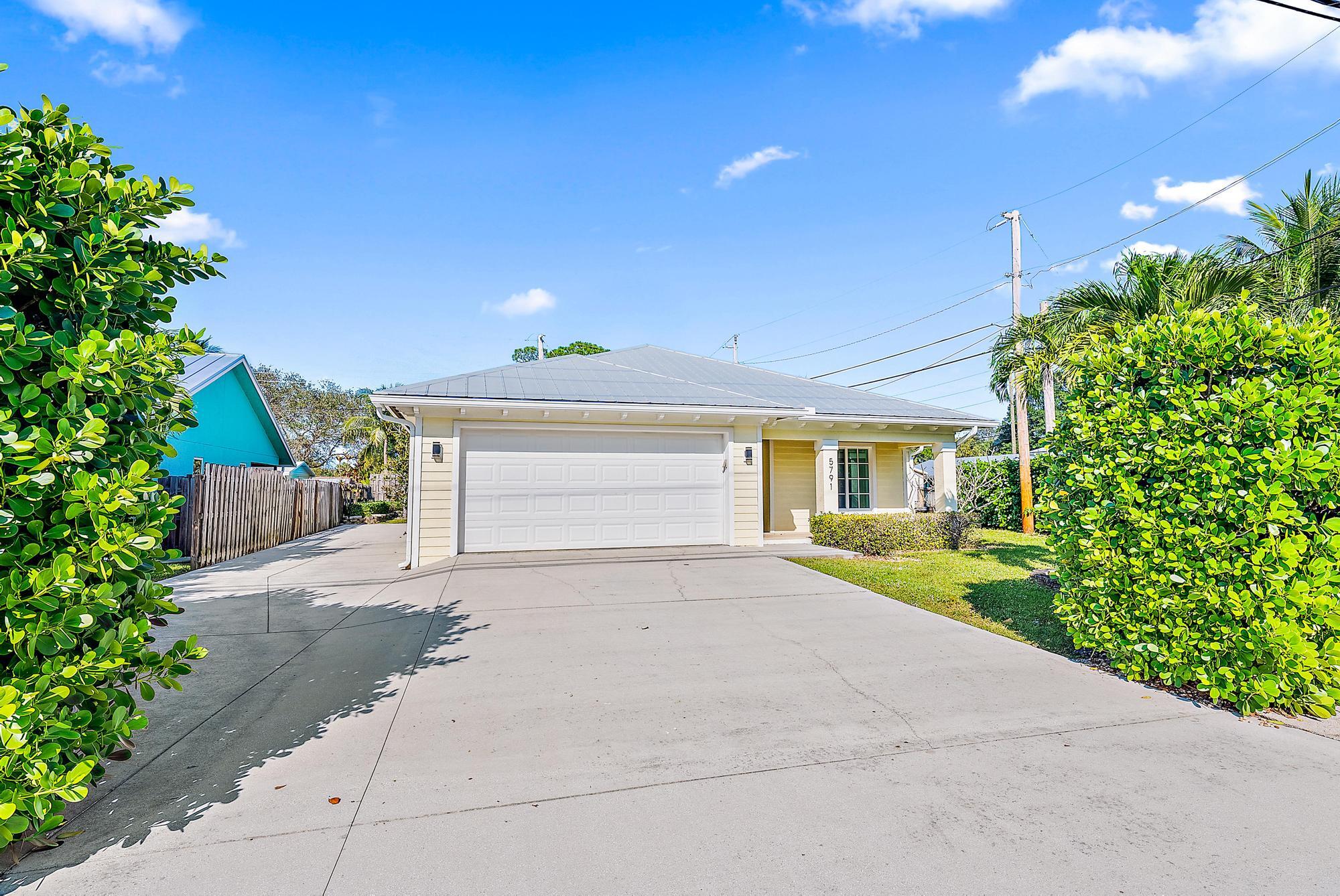 5791 Roebuck Road Jupiter, FL 33458 - Photo 1 of 23 a front view of a house with a yard and a garage
