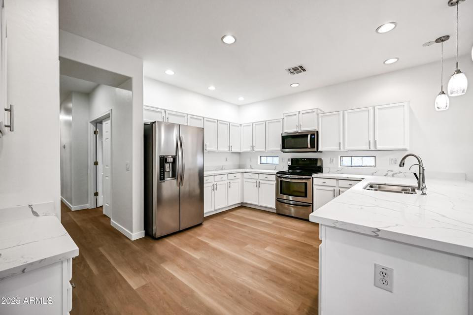 865 South Oak Street Gilbert, AZ 85233 - Photo 9 of 27 a kitchen with kitchen island a refrigerator sink and white cabinets