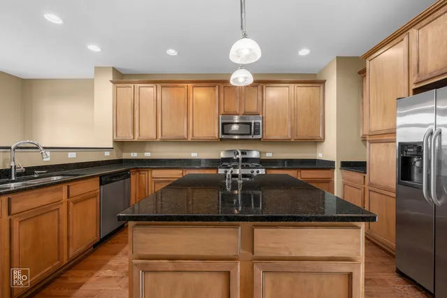 a kitchen with kitchen island granite countertop a sink cabinets and stainless steel appliances