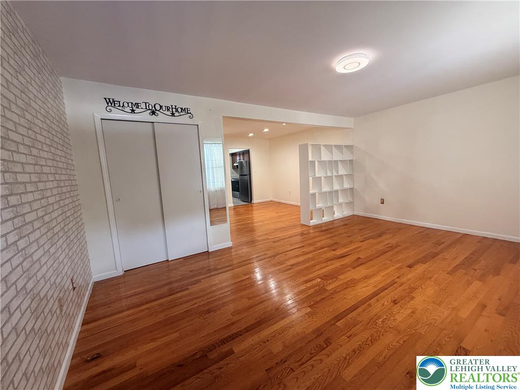 170 Springhouse Road Allentown, PA 18104 - Photo 2 of 23 Rich hardwood flooring extends throughout this versatile living area, complemented by clean, painted brick accents.