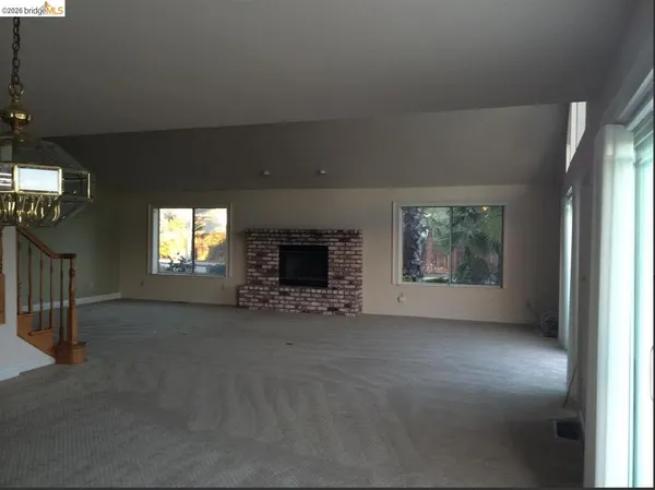 an empty room with windows and fireplace