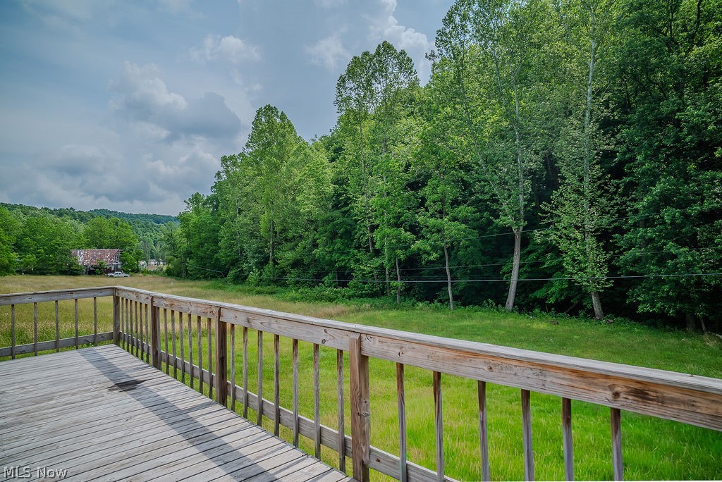 967 Buck Run Road Mineral Wells, WV 26150 - Photo 49 of 50 Spacious outdoor deck with natural wood railing overlooking a verdant landscape of trees and open grassy areas