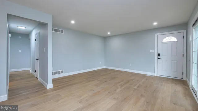 a view of an empty room with wooden floor and closet area