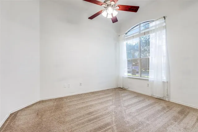 an empty room with a window and a fan