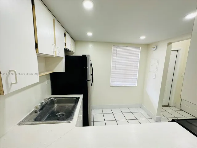 a kitchen with a sink a refrigerator and cabinets